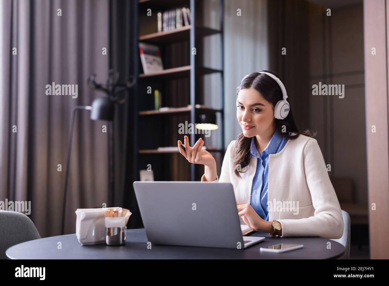 young freelancer in headphones sitting near laptop in restaurant Stock Photo