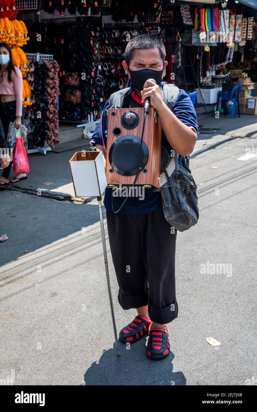 A young blind man slowly walks though the Chatachuk Market singing to tunes  played and amplified on his music box Stock Photo - Alamy