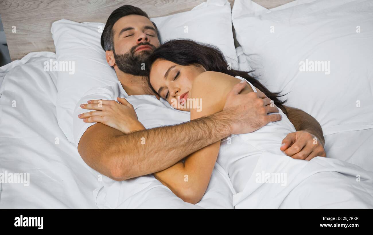 young couple hugging while sleeping on white bedding Stock Photo ...