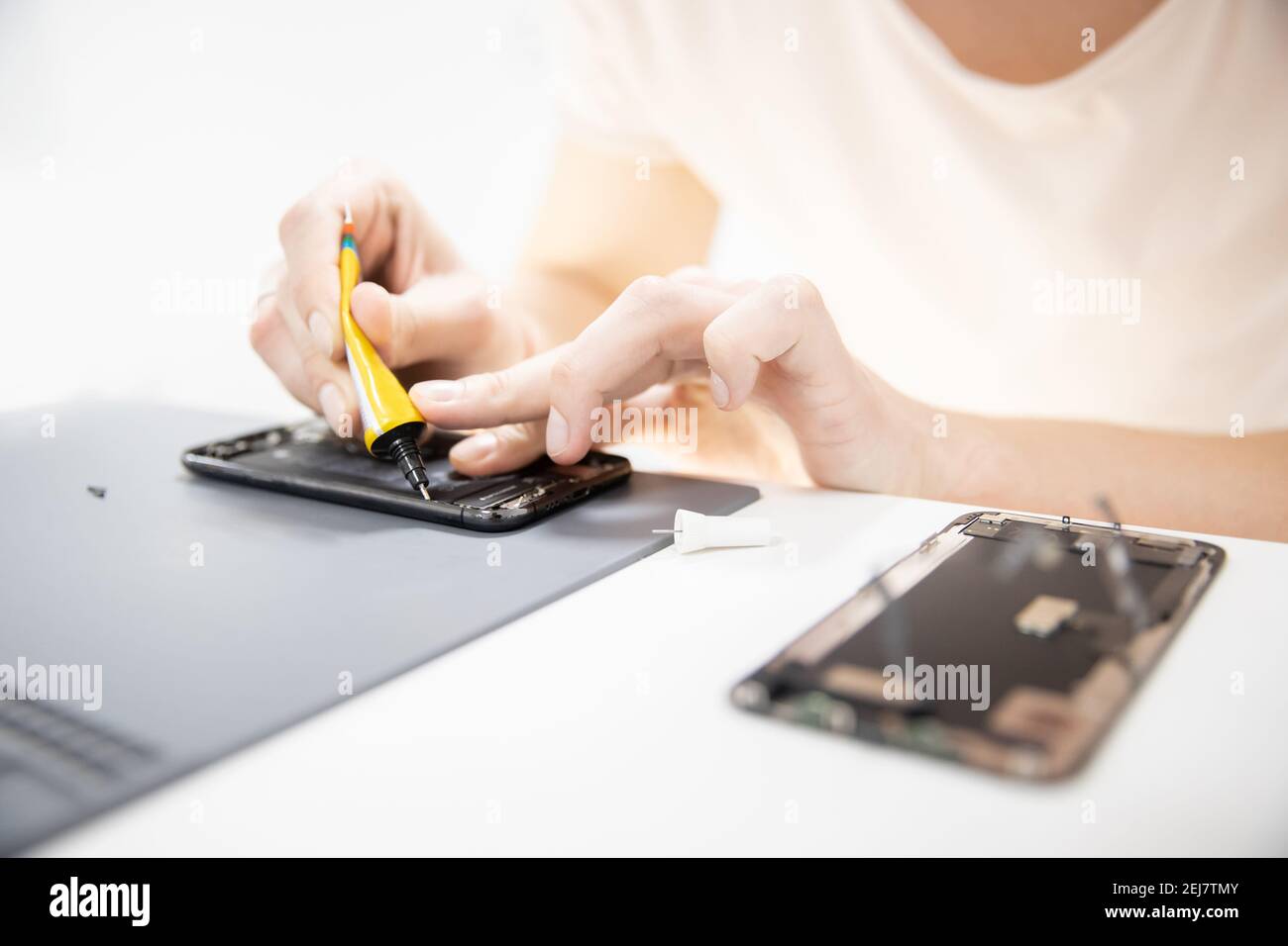 Master disassembles modern mobile phone, repairs and replaces battery, broken screen. Stock Photo