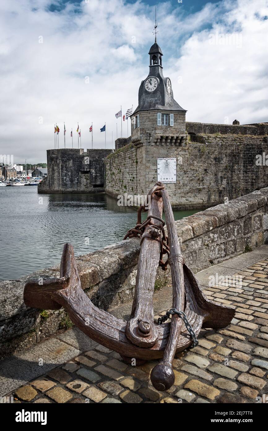 Old rusty anchor at the entrance of the closed city of Concarneau in Finistère, Brittany, France Stock Photo