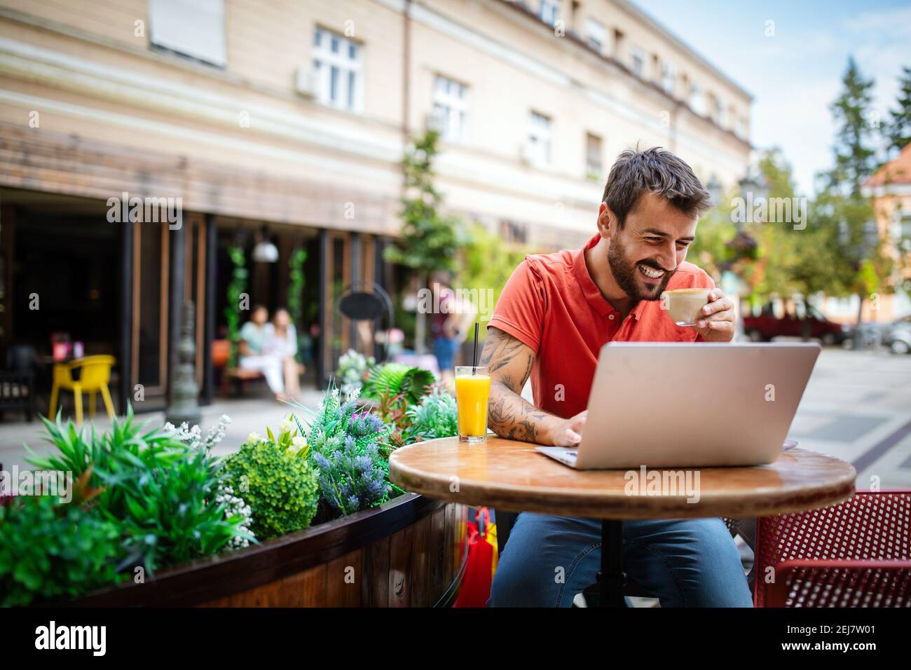 Young man having fun, enjoying free time on laptop and smiling while sitting in cafe Stock Photo