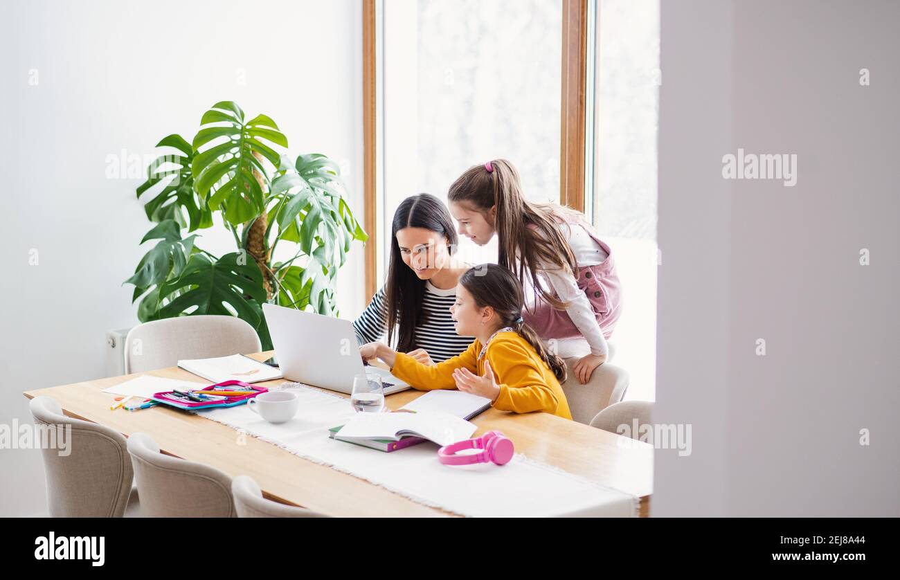 Mother with school girls indoors at home, distance learning and home ...