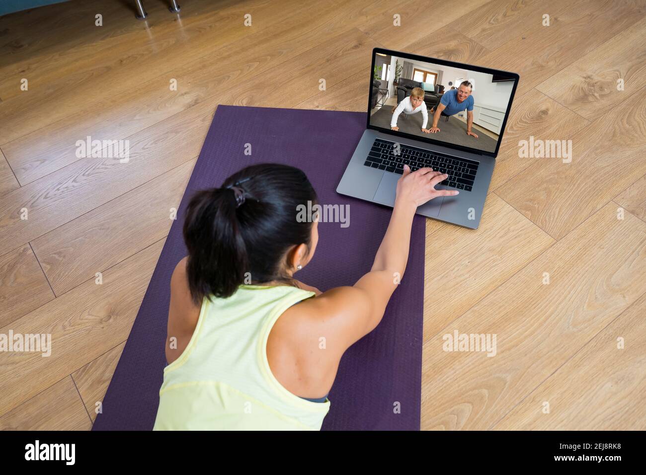 People exercising at home connected to online fitness class on laptop