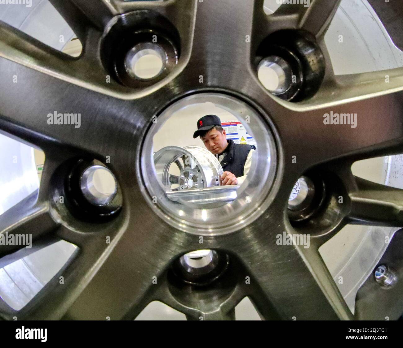 A Chinese worker checks aluminum car rims on the production line at a ...