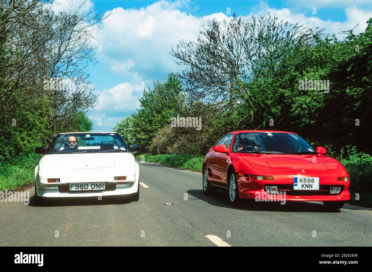1998 England two Toyota mr2 cars - A red Japanese import Toyota MR2 mk2 turbo and a white Toyota MR2 mk1 car with the white MR2 mk1 mr2 overtaking the red Toyota MR2 mk2 turbo on a country lane England GB UK Europe Stock Photo