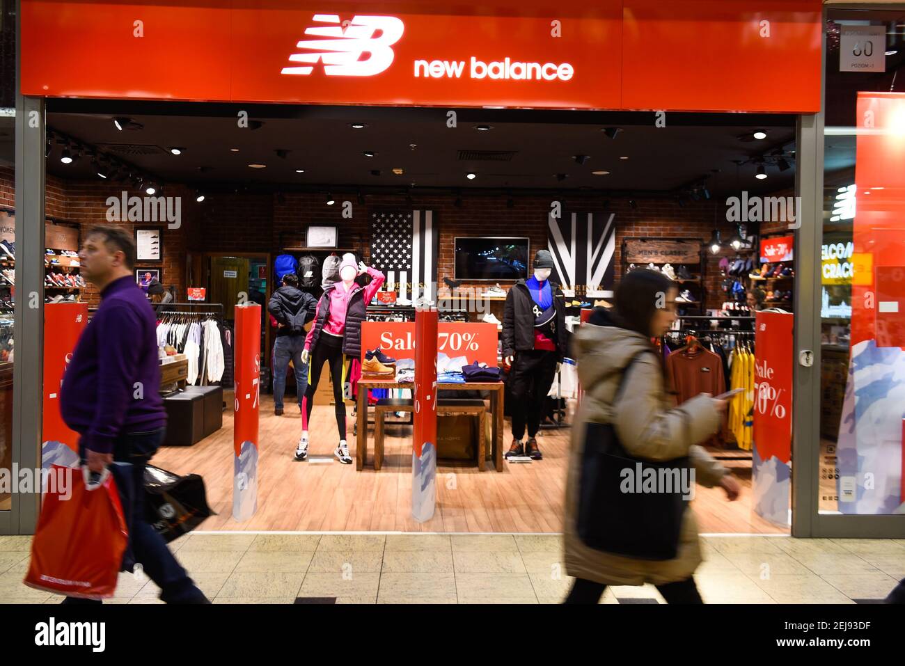 People walk pass a New Balance shop in Krakow. Photo by Omar