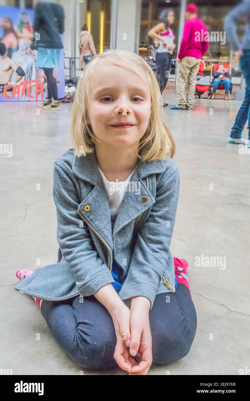 Girl 5-6 year old on her knees smiling on a dance floor Stock Photo