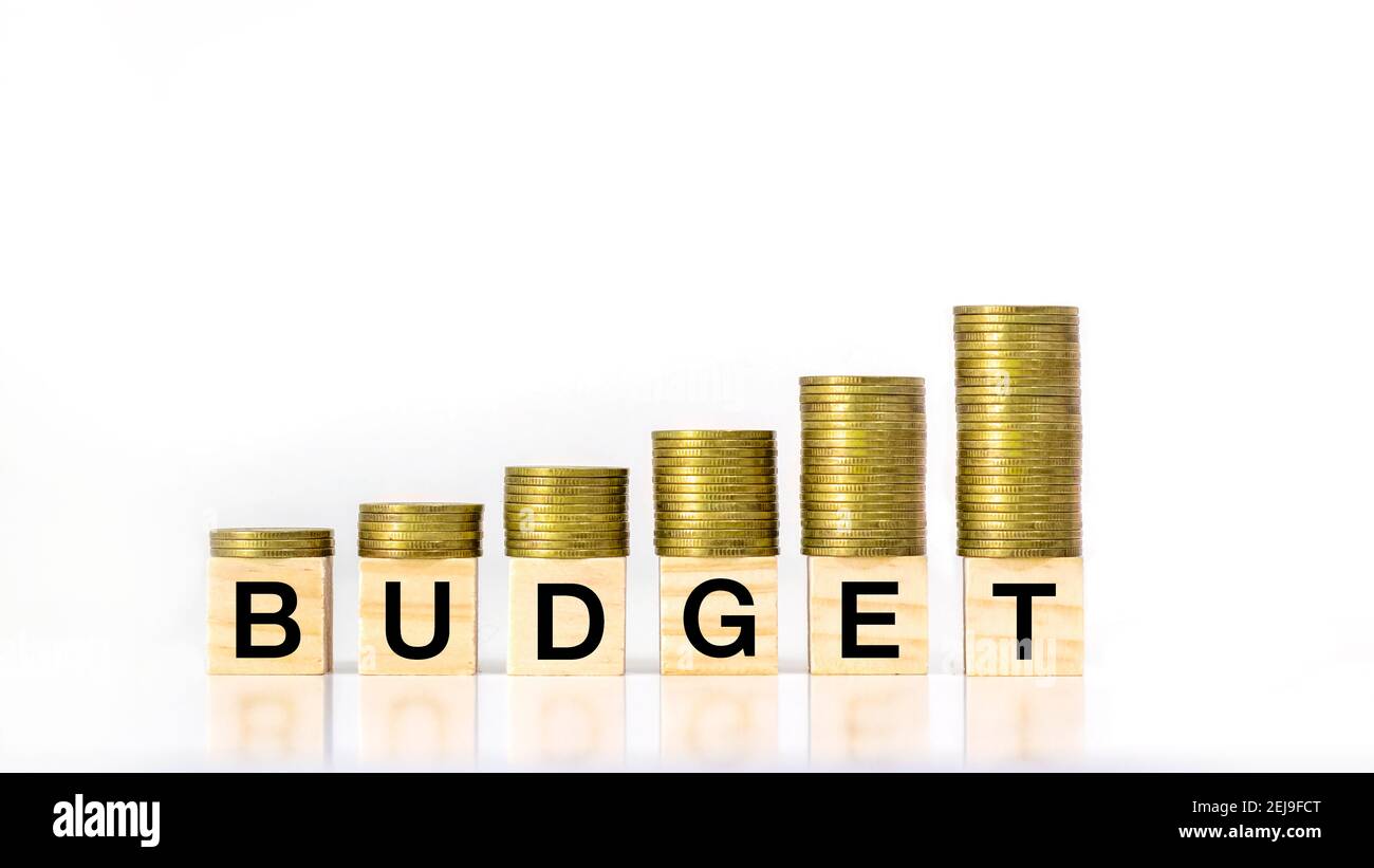 A growing stack of coin steps on a wooden block labeled budget on a white background, investment budget idea and annual budget. Stock Photo