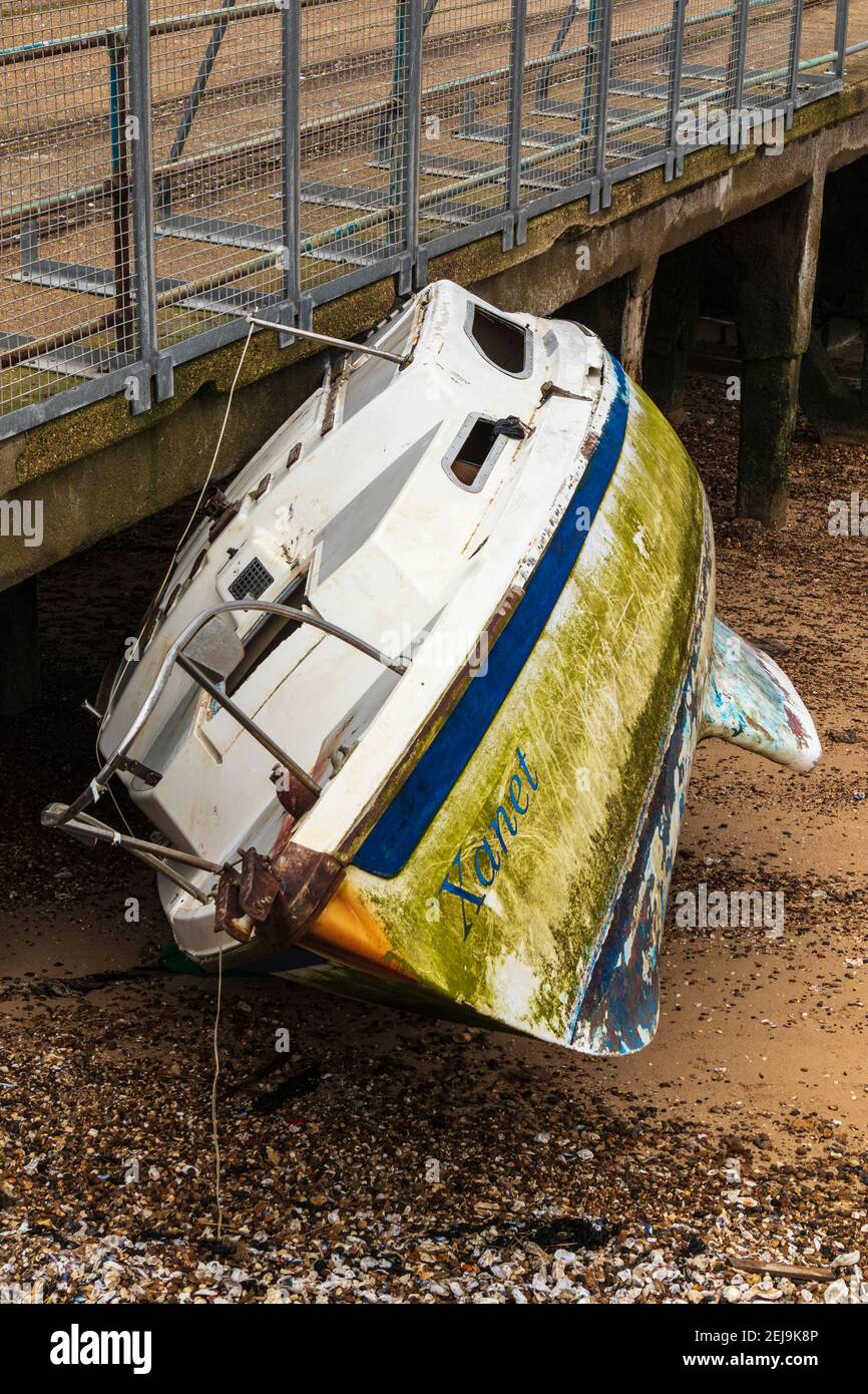 Derelict Yacht 'Xanet' Abandoned on Beach at Shoeburyness Against Old Barge Pier Stock Photo