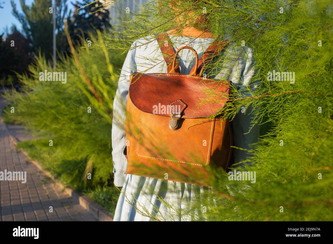 Girl wear leather fashion handmade bag. Leather backpack craft product. Stock Photo