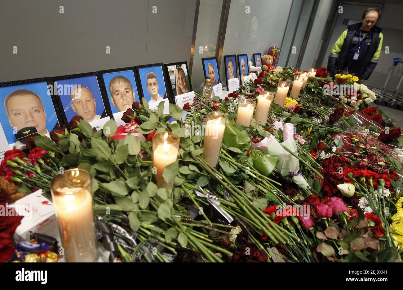 Flowers and candles are placed in front of the portraits of the victims