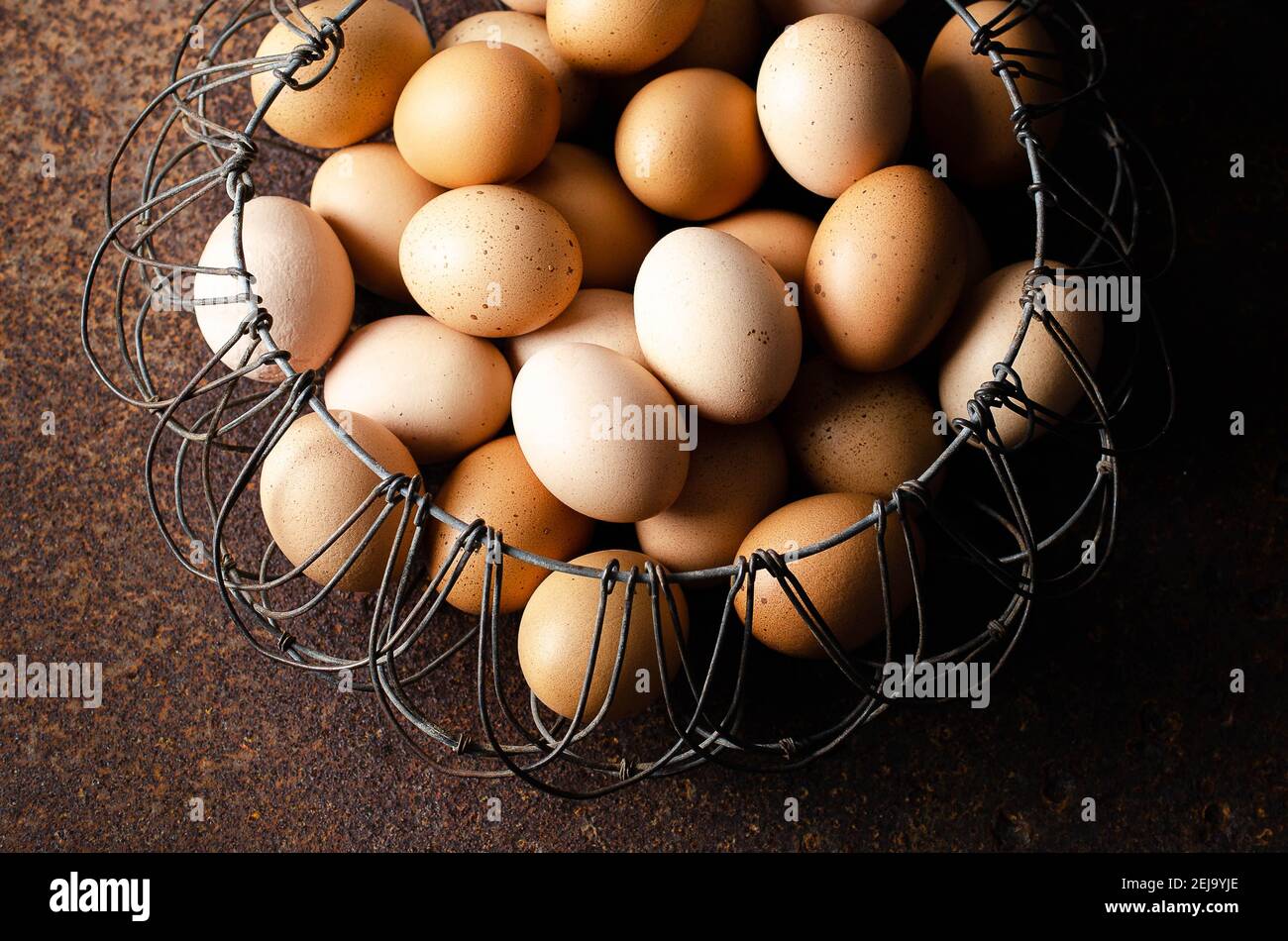 Eggs in a wired basket on a dark backdrop. Stock Photo
