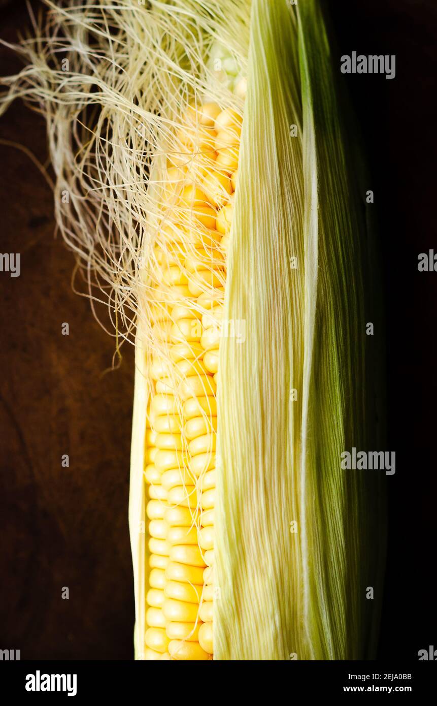 Yellow corncob with leaves and silk. Close-up. Stock Photo