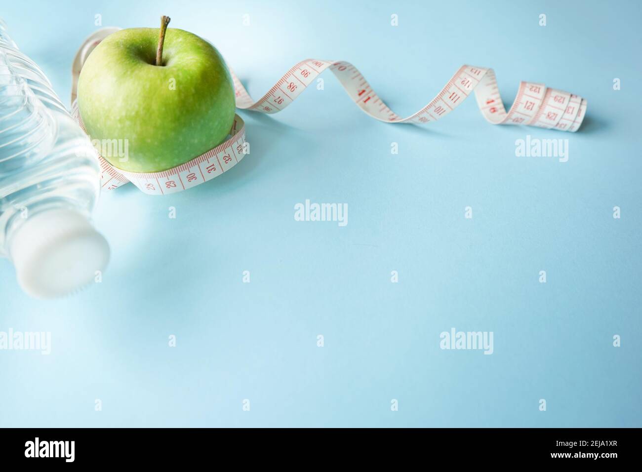 Concept of a healthy lifestyle. Detox water, glucose meter and green apple on a blue background