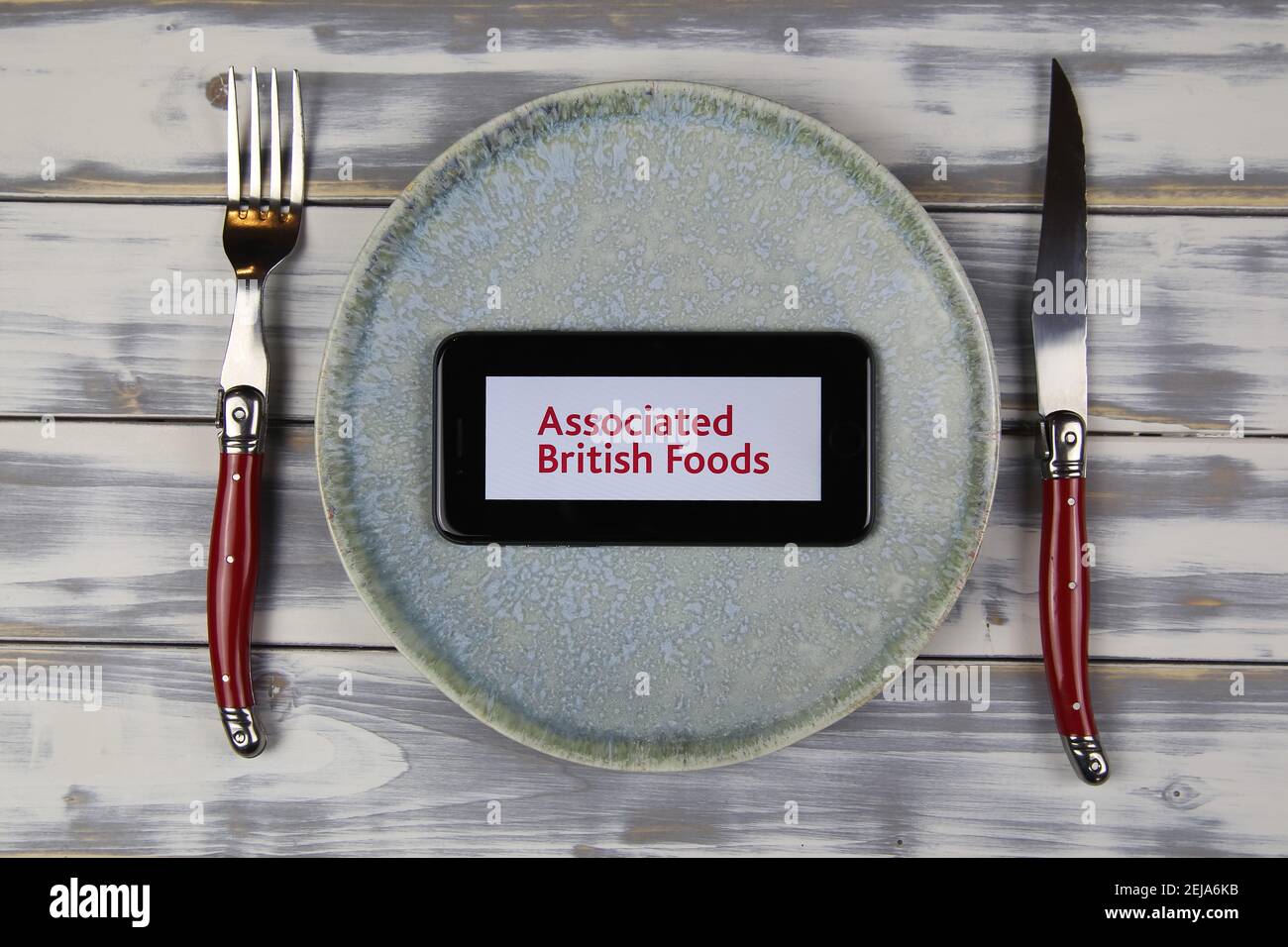 Viersen, Germany - February 9. 2021: Closeup of smartphone screen with logo lettering of associated british foods plc on plate with cutlery Stock Photo