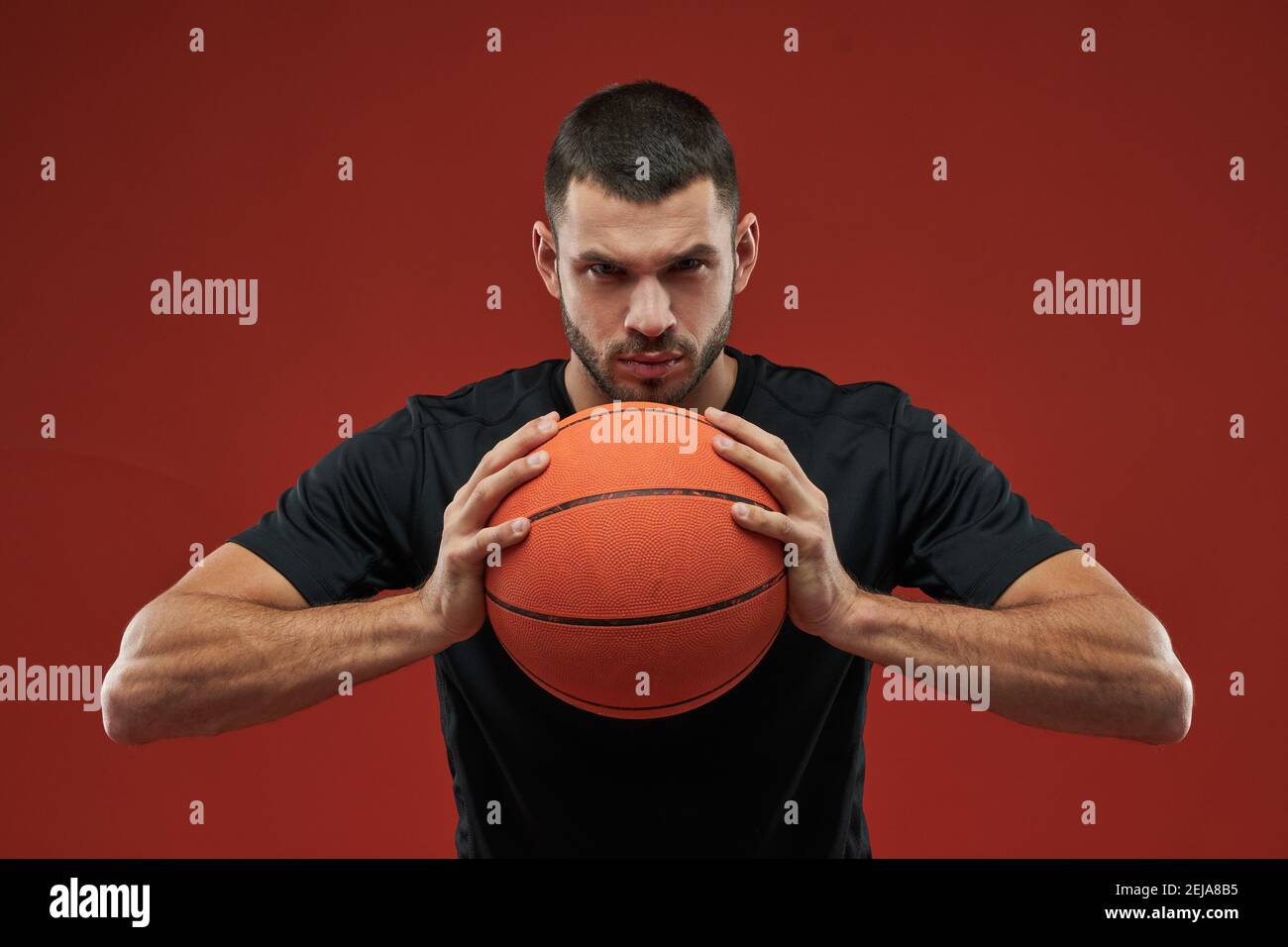 Waist up portrait of handsome strong basketball player holding with