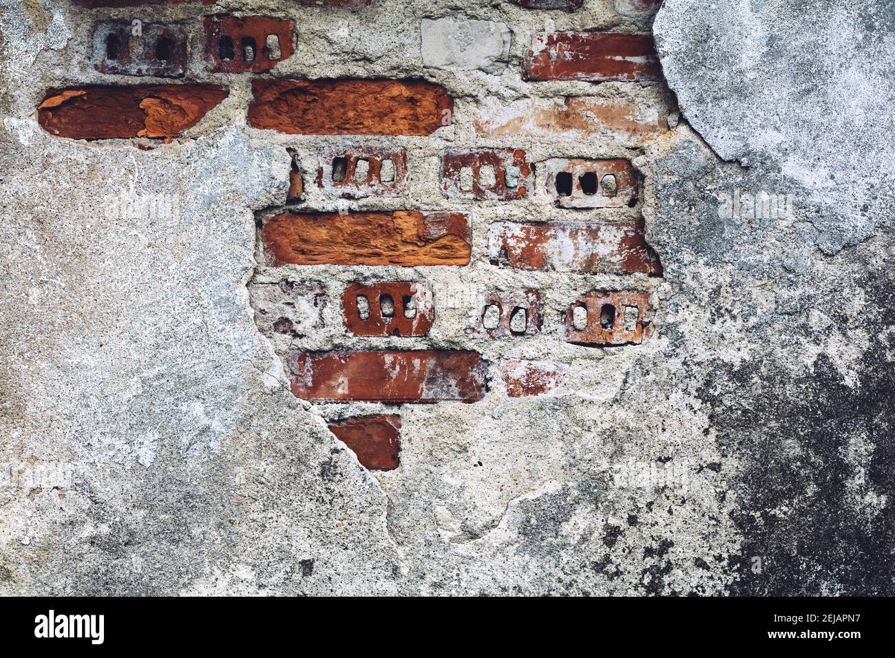 Damaged old wall with bricks red showing through. Grunge background. Stock Photo