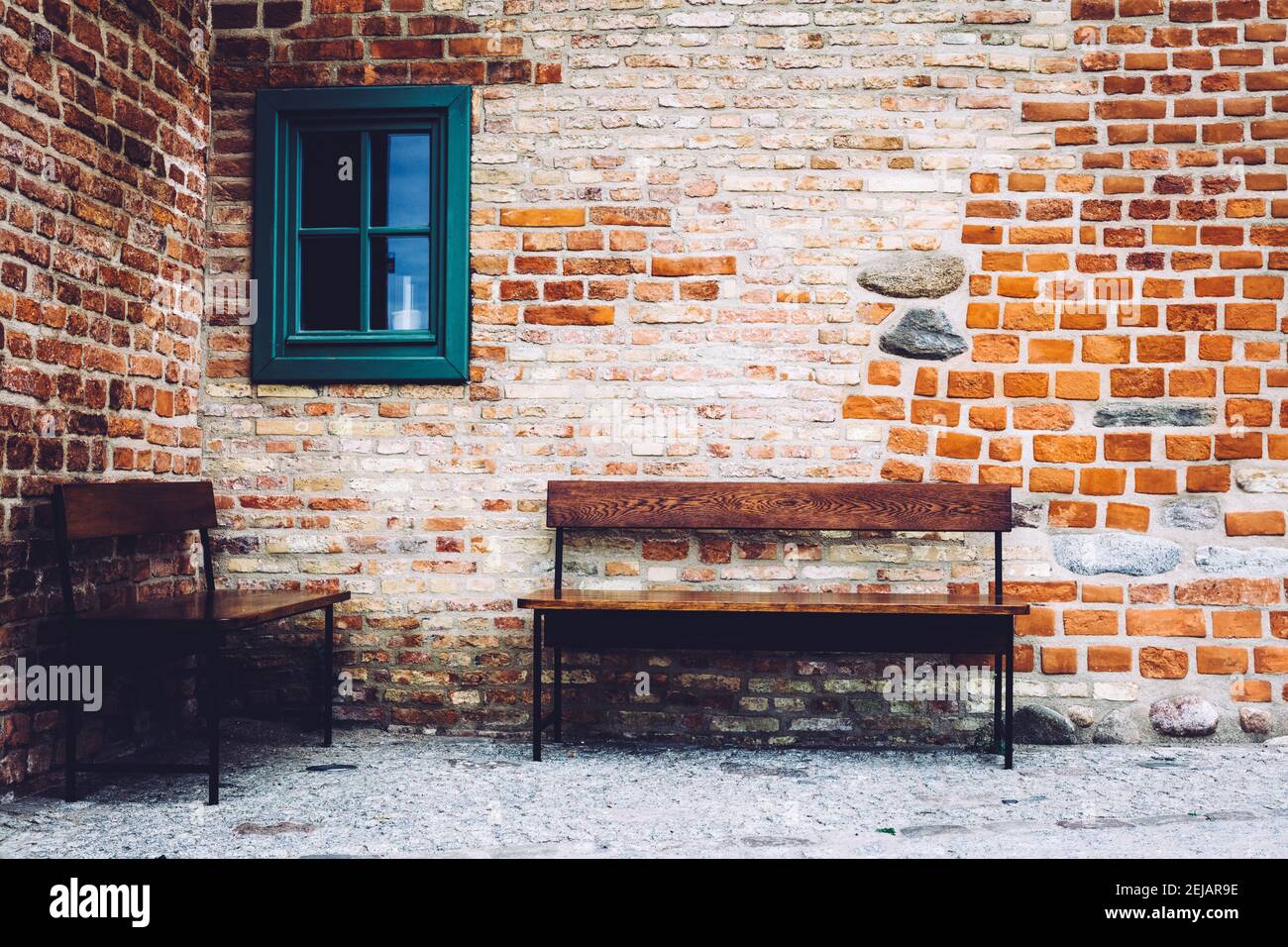Two wooden benches standing in front of old brick building with green ...