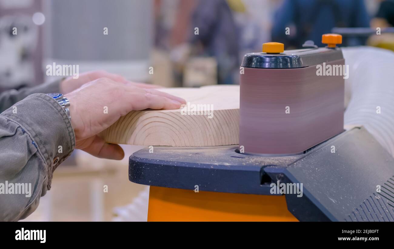Man carpenter using belt sander machine, polishing wood product: close up Stock Photo