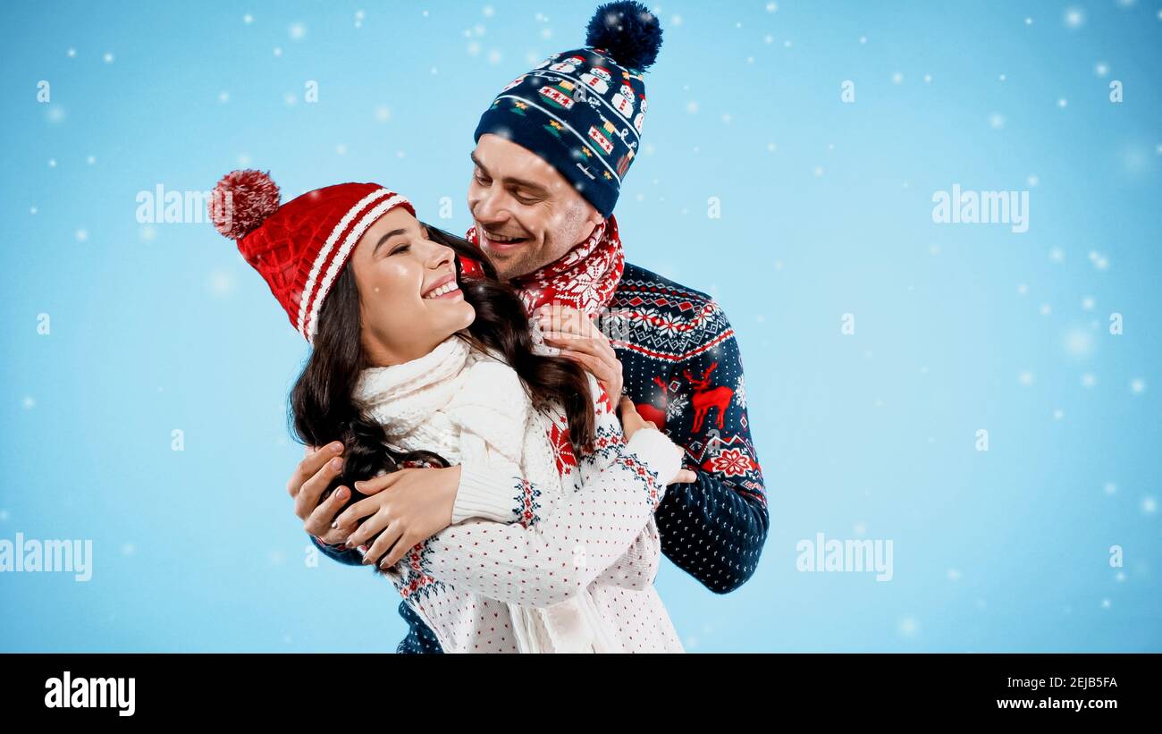 Hugging Sweater Cheerful couple in warm hats and sweaters hugging on blue background ...