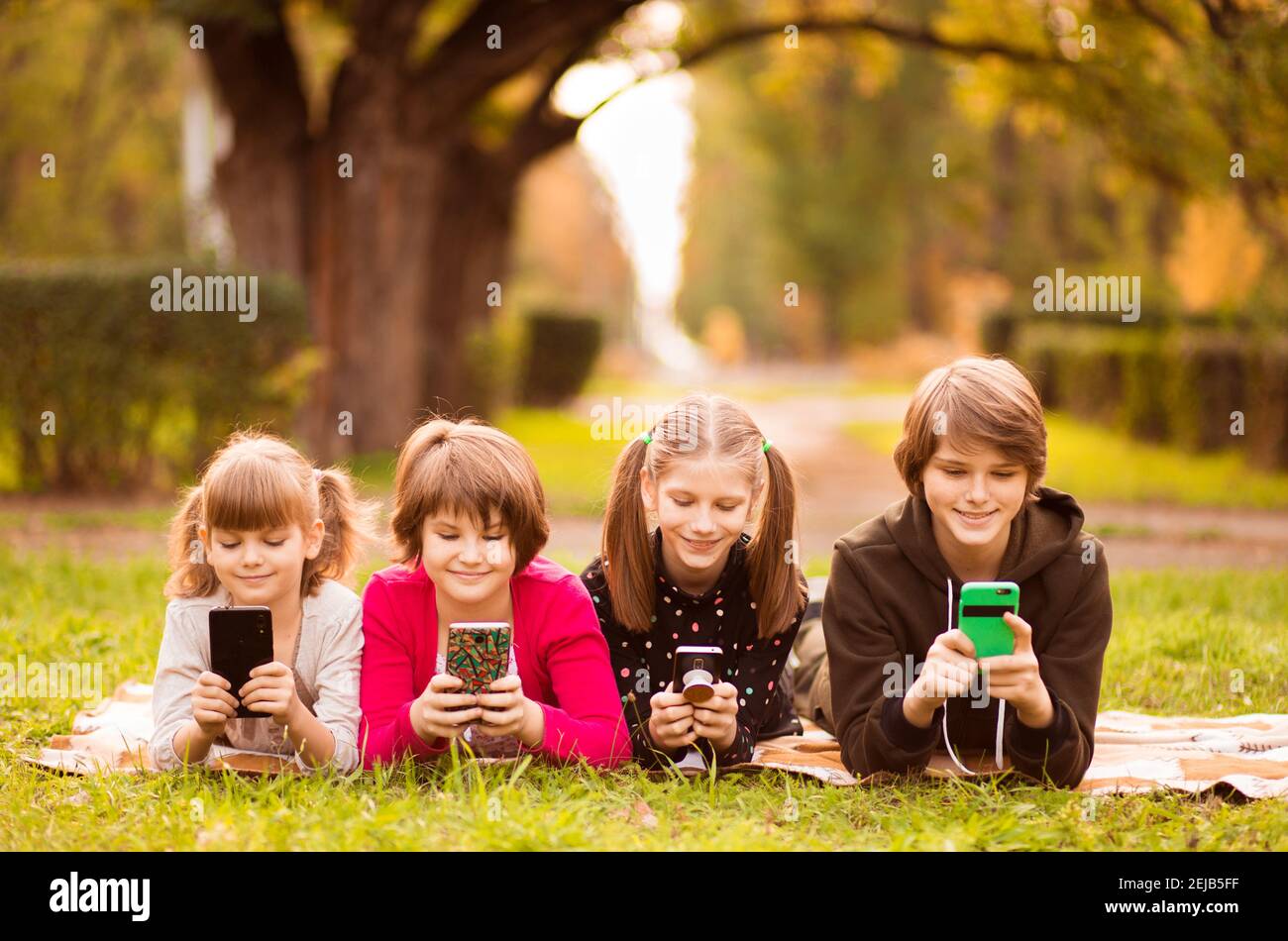 Smartphone addiction group of little children watching film movie cartoon together on digital tablet. Kids playing with phone together Stock Photo