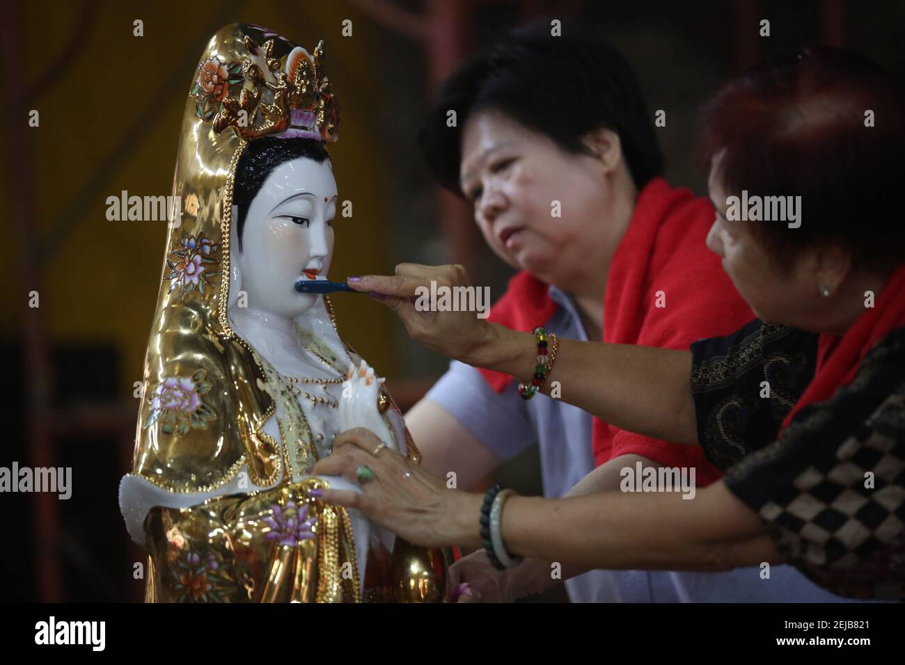 Women brush a statue during the celebration at the Amurva Bhumi temple