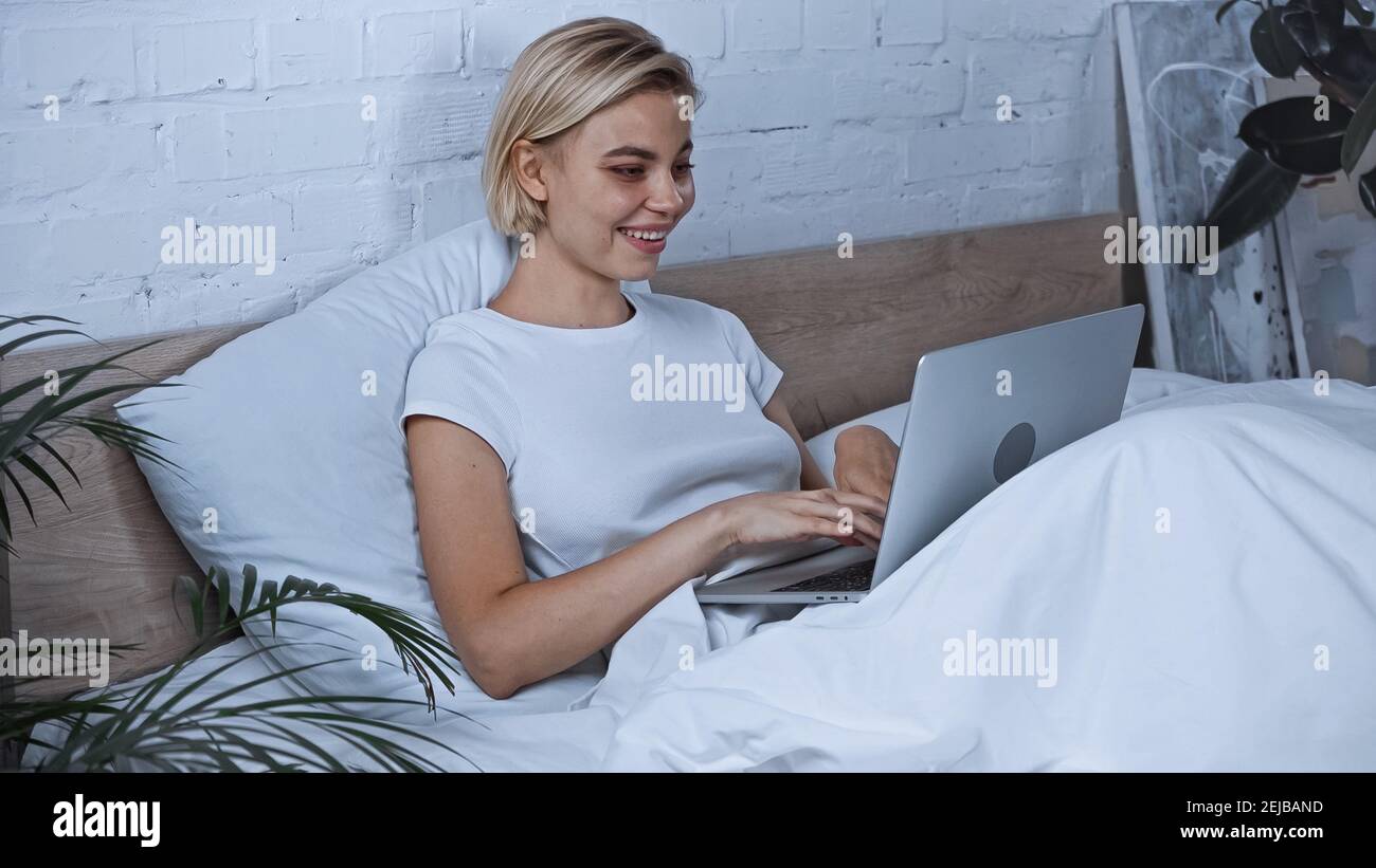 cheerful blogger typing on laptop in bedroom Stock Photo - Alamy