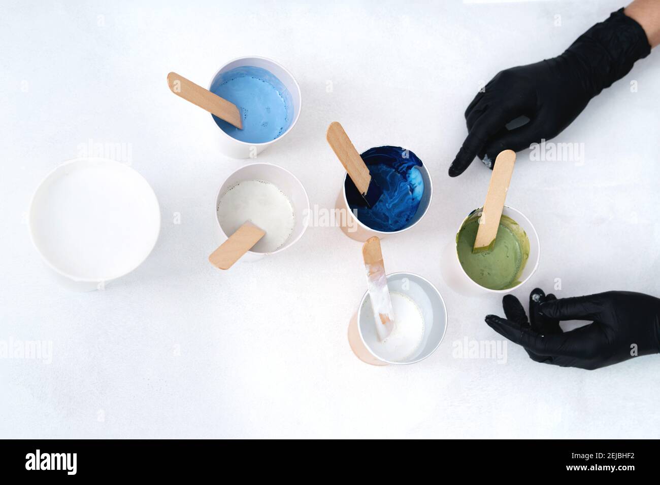 The process of creating a painting using fluid art technique. Hands with gloves and. Artistic background. Stock Photo