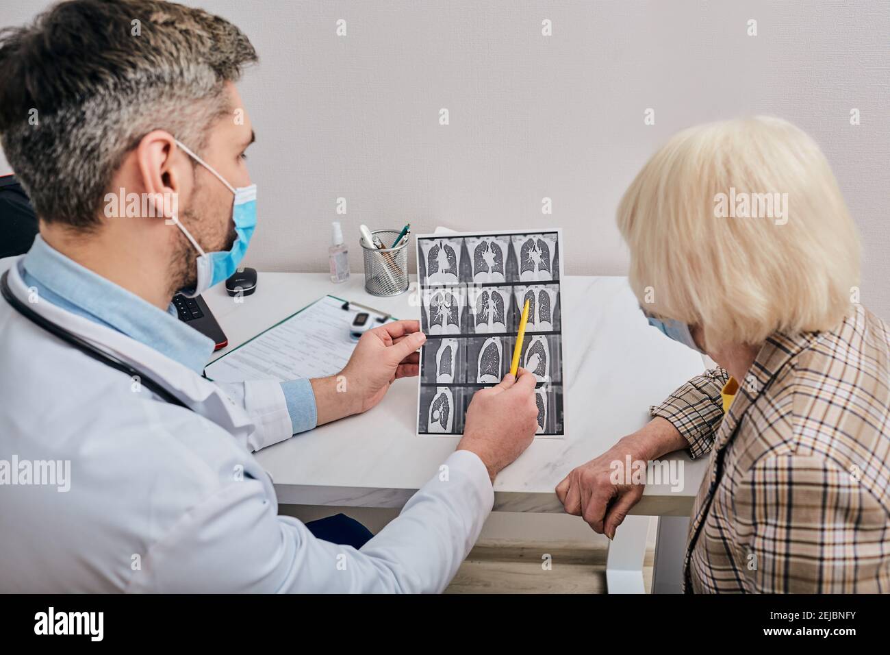 doctor shows a senior patient a CT scan of her lungs. Pneumonia, coronavirus, lung disease Stock Photo