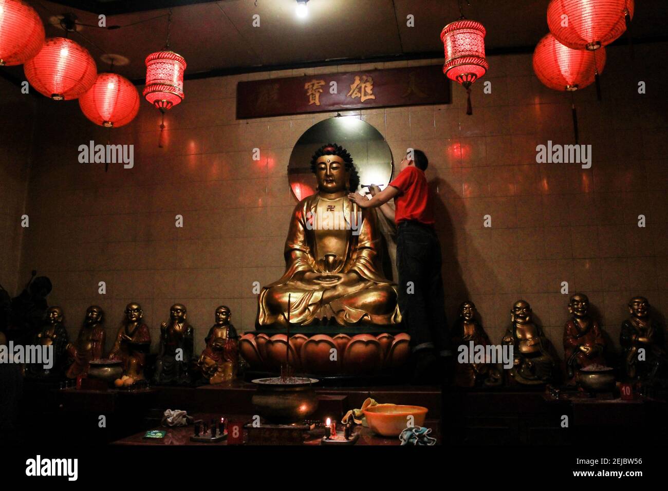 A man brushes a statue during the celebration at Dharma Ramsi temple in