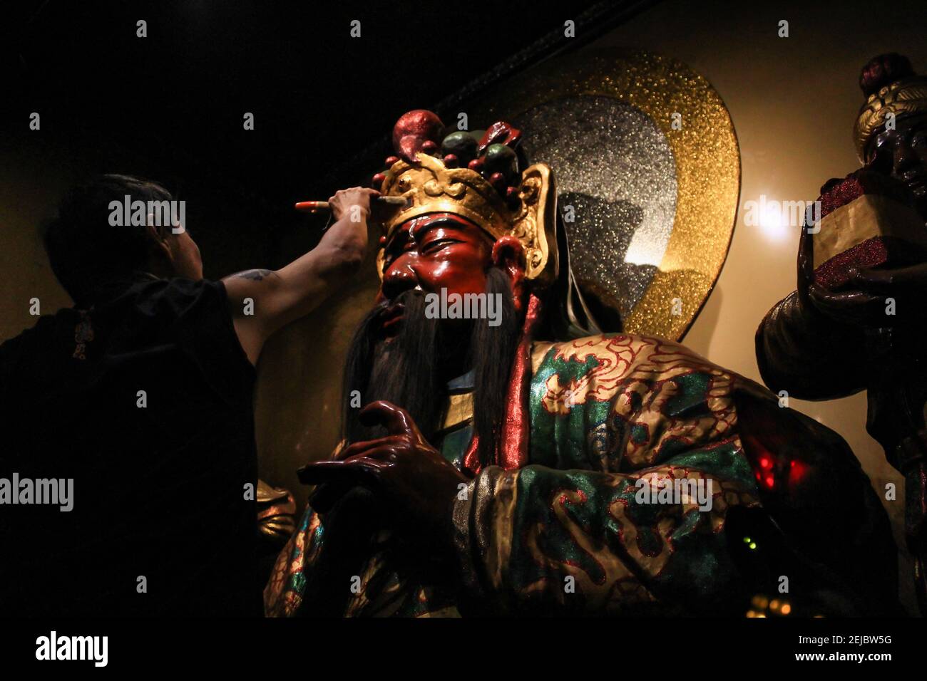 A man brushes a statue during the celebration at Dharma Ramsi temple in