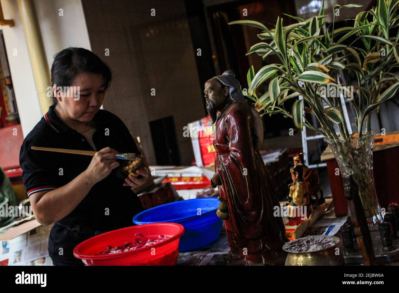 A woman brushes a statue during the celebration at Dharma Ramsi temple