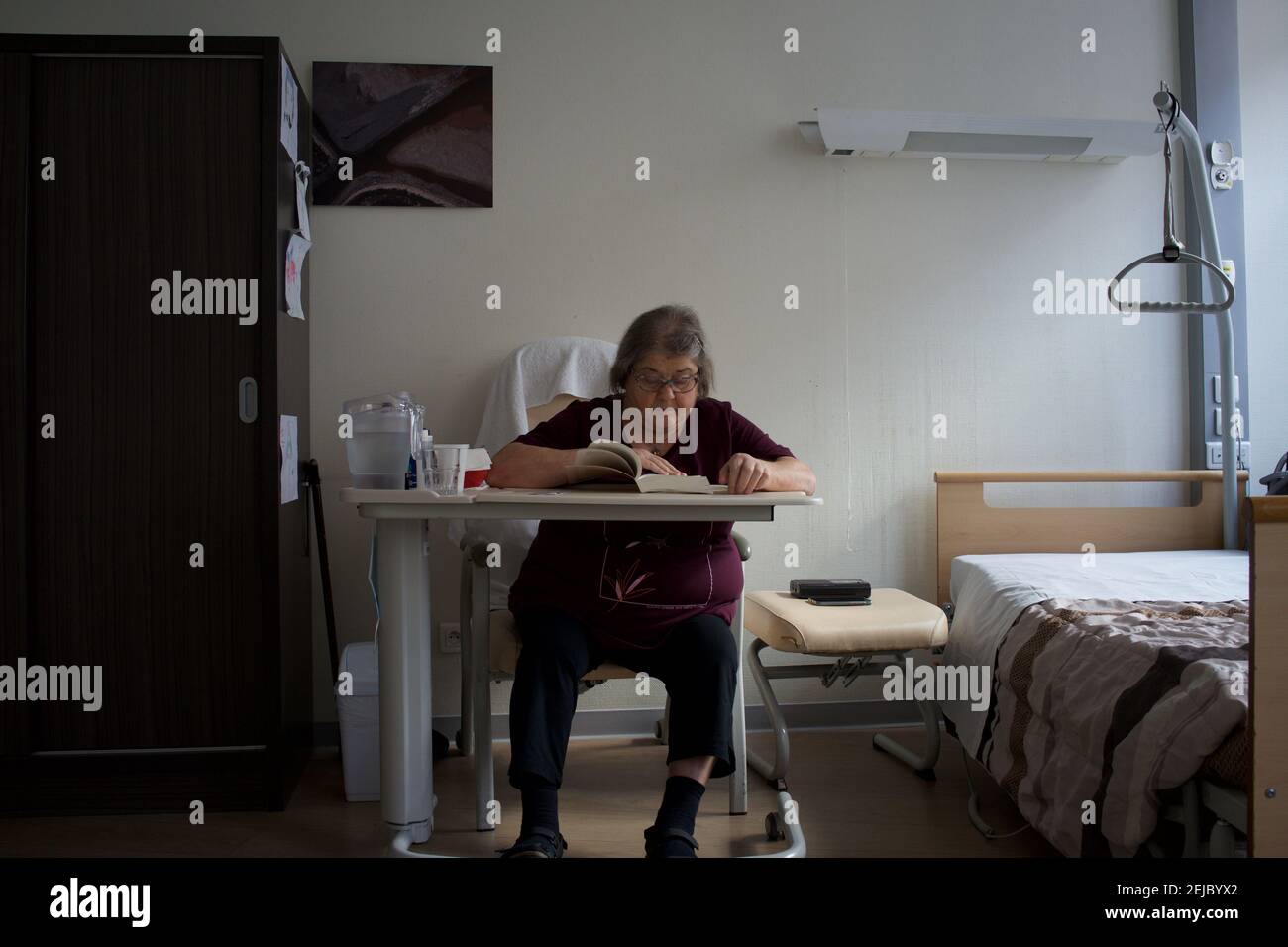 Patient in room, reading book, residential care home - Paris, France Stock Photo