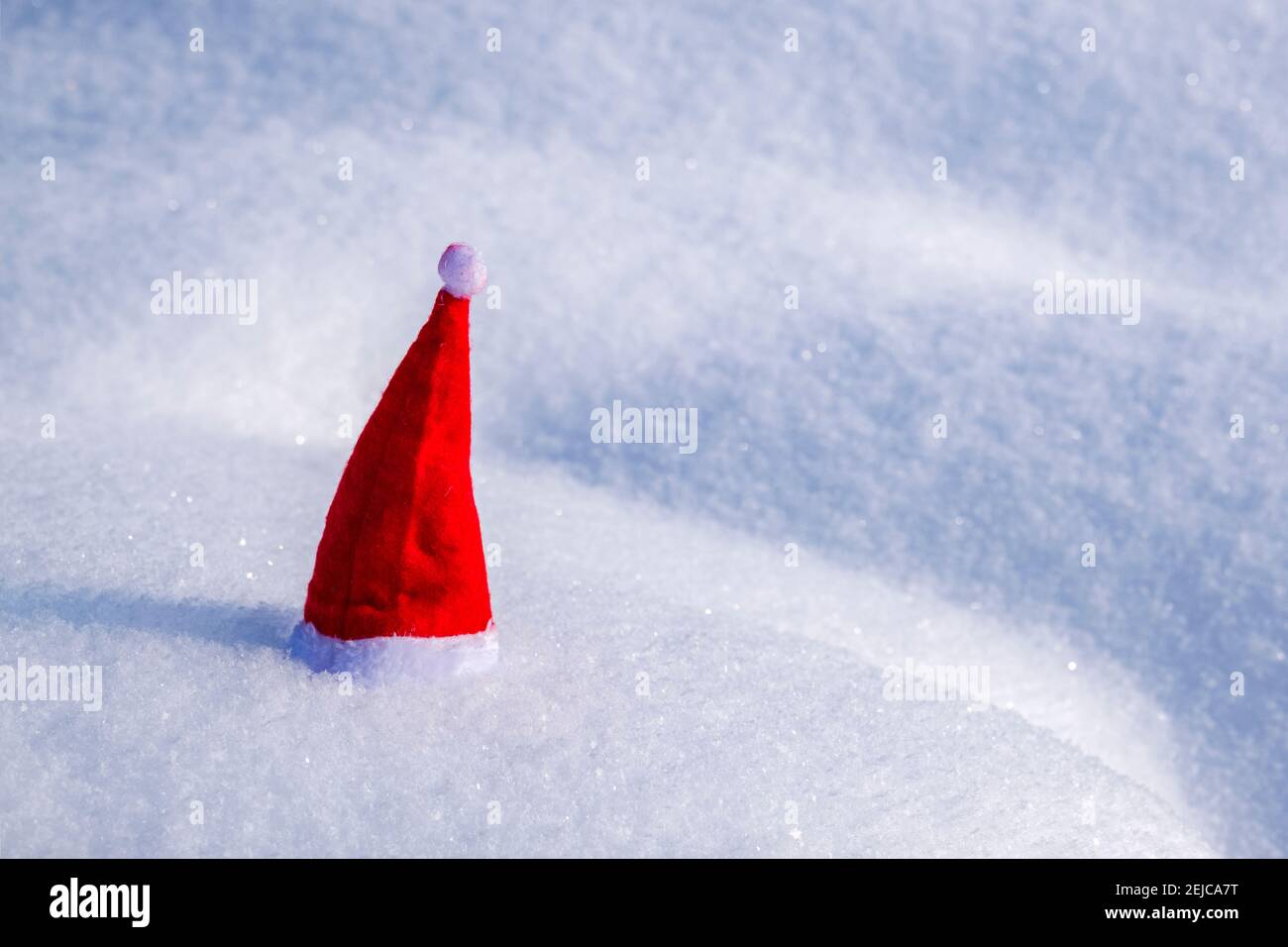 A small red christmas cap placed on snow. Stock Photo