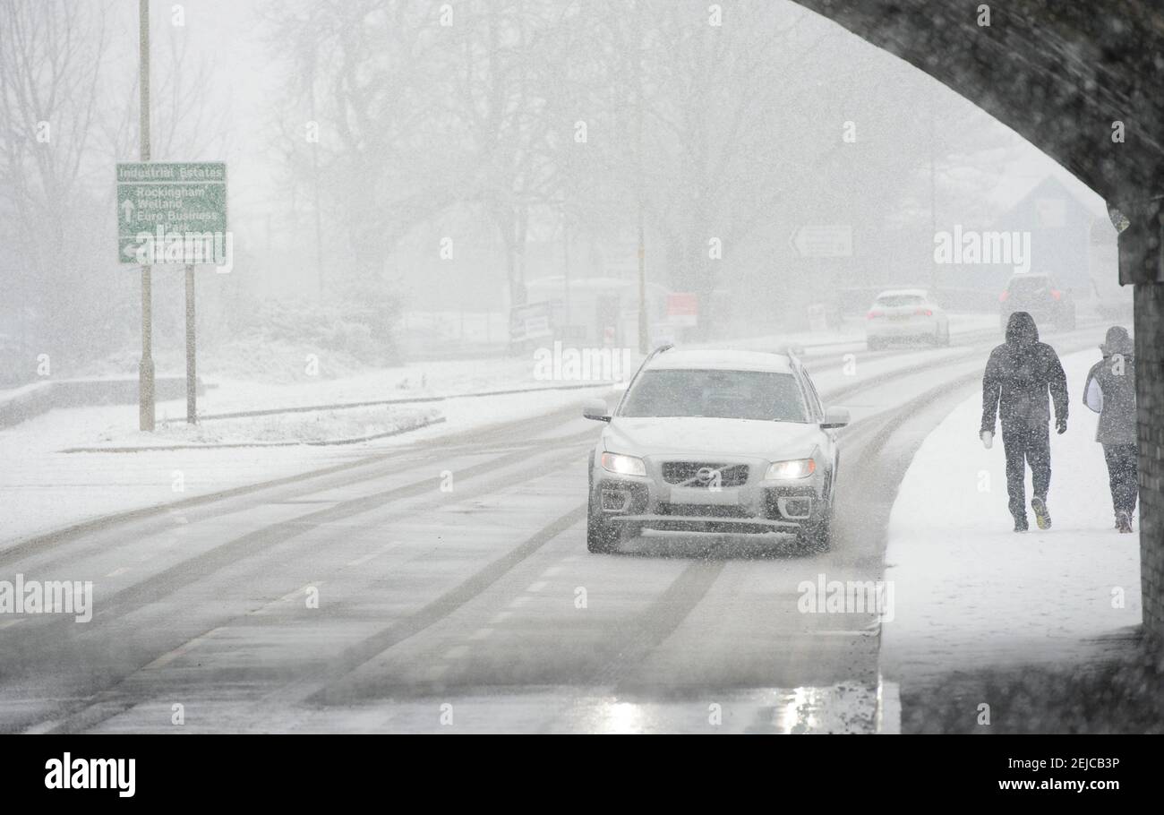 Cars driving on a snow covered road on a winter's day in Market Harborough, Leicestershire, United Kingdom. Stock Photo