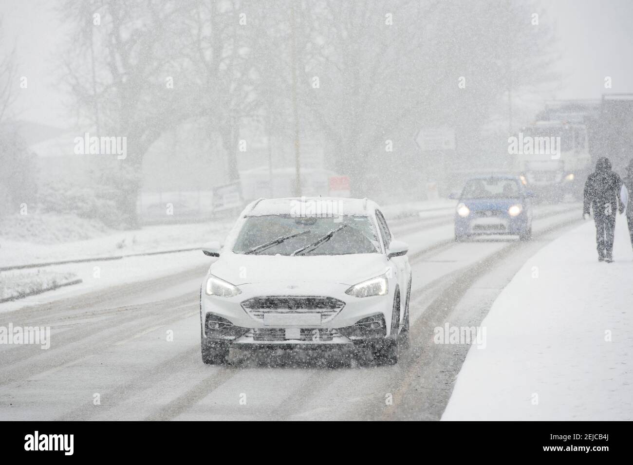 Cars driving on a snow covered road on a winter's day in Market Harborough, Leicestershire, United Kingdom. Stock Photo