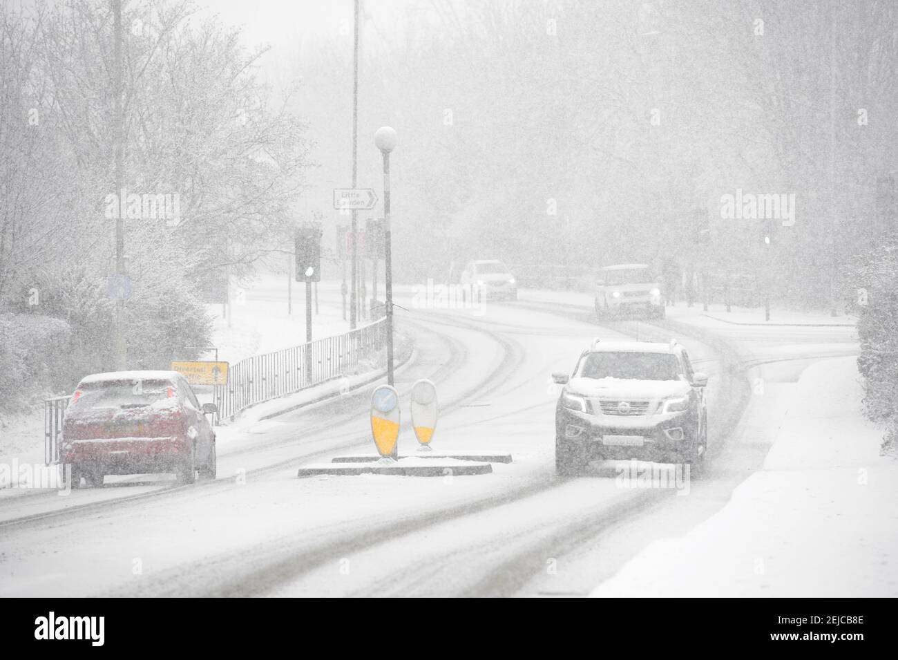 Cars driving on a snow covered road on a winter's day in Market Harborough, Leicestershire, United Kingdom. Stock Photo