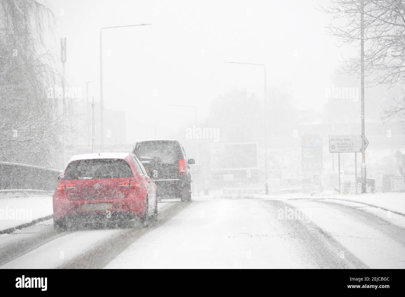 Cars driving on a snow covered road on a winter's day in Market Harborough, Leicestershire, United Kingdom. Stock Photo