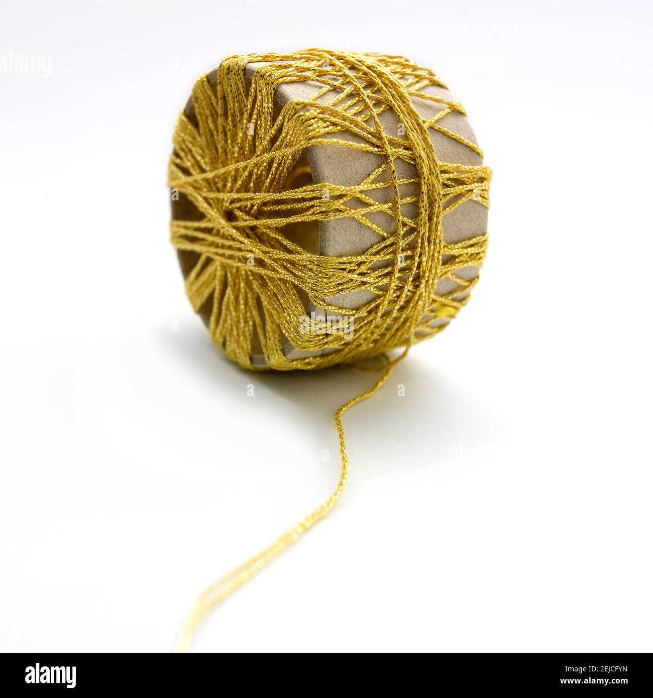 Bobbin of golden thread on white background Stock Photo