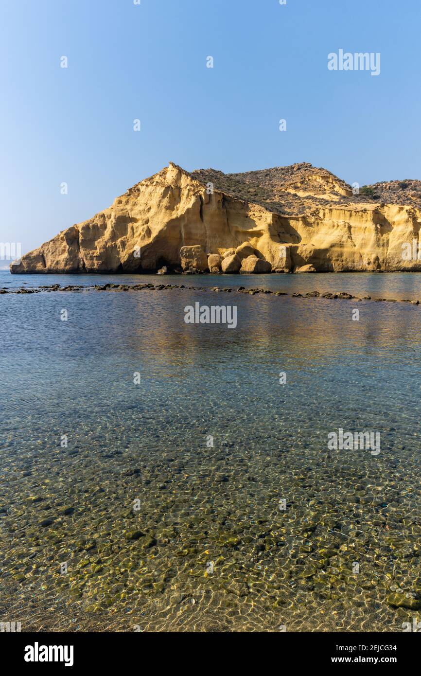 A vertical view of calm idyllic ocean water in the Mediterranean with yellow sandstone cliffs behind Stock Photo