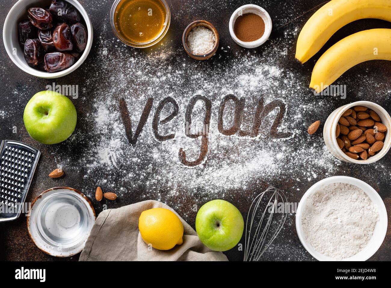 vegan baking ingredients, utensils and word Vegan on dark background
