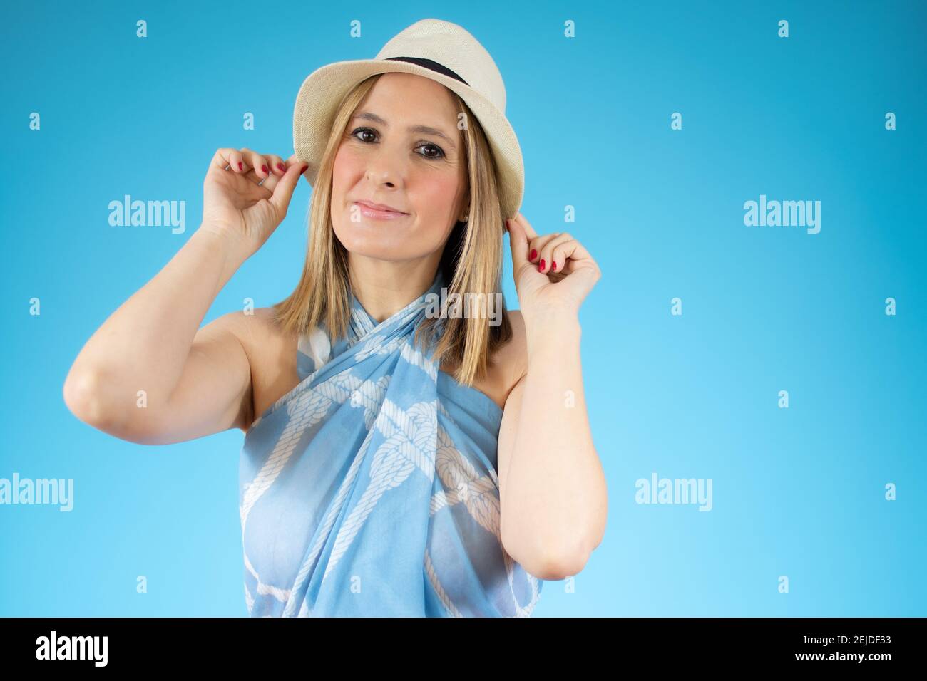 Close up portrait of young smiling woman in straw hat over blue ...