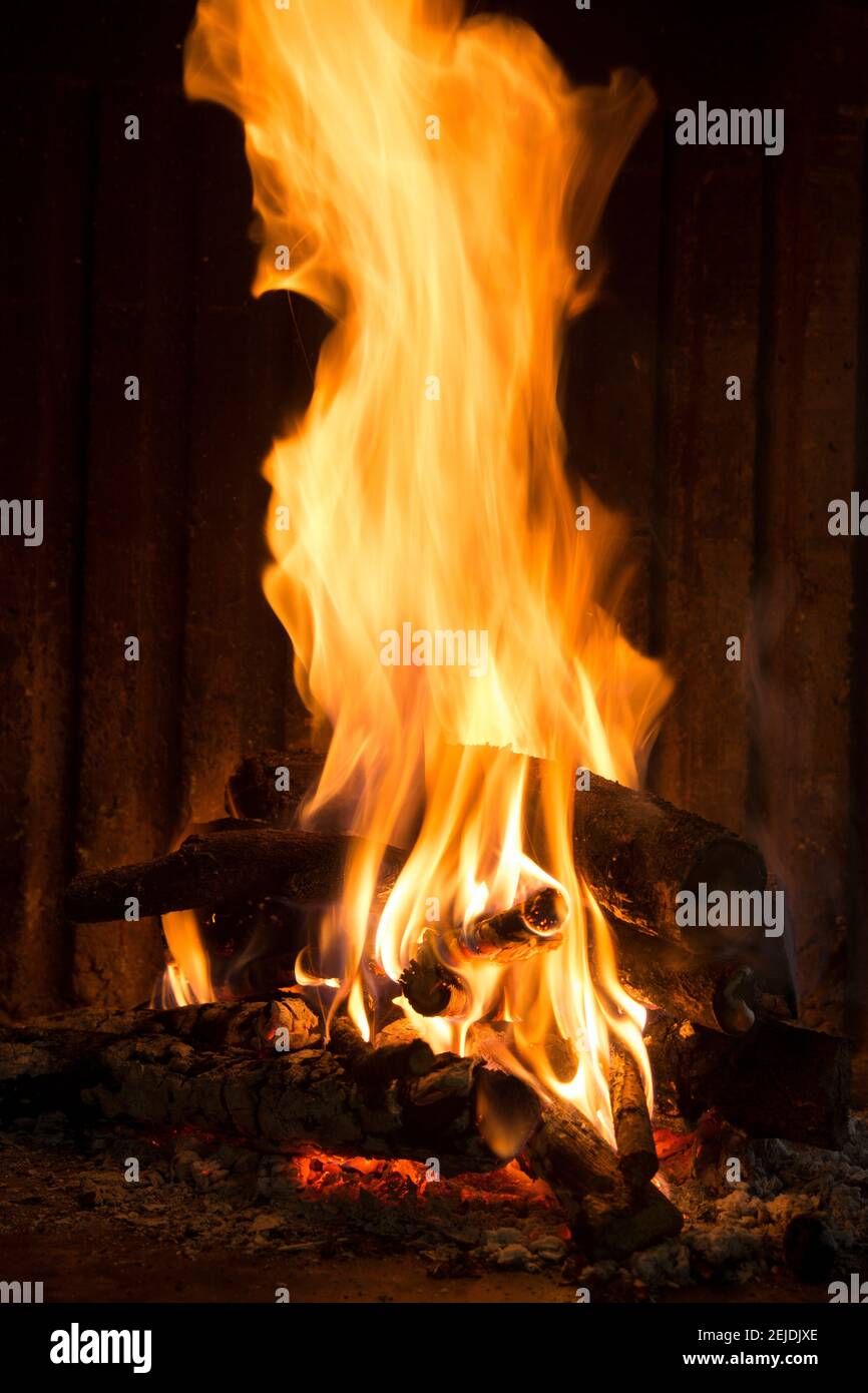 Warm flames dance in a cozy fireplace setting during a chilly evening indoors Stock Photo