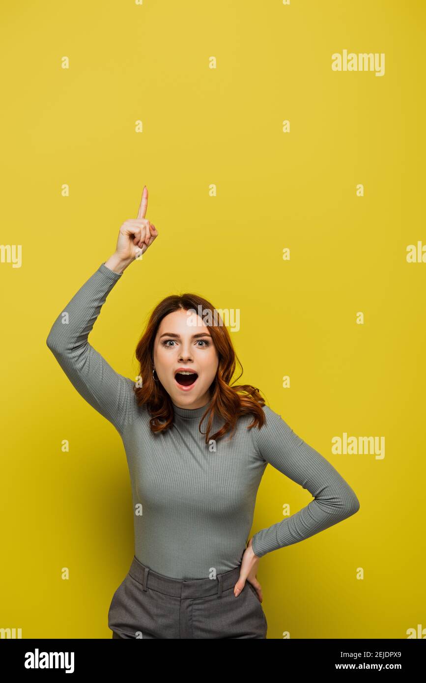 amazed woman having idea and looking at camera on yellow Stock Photo