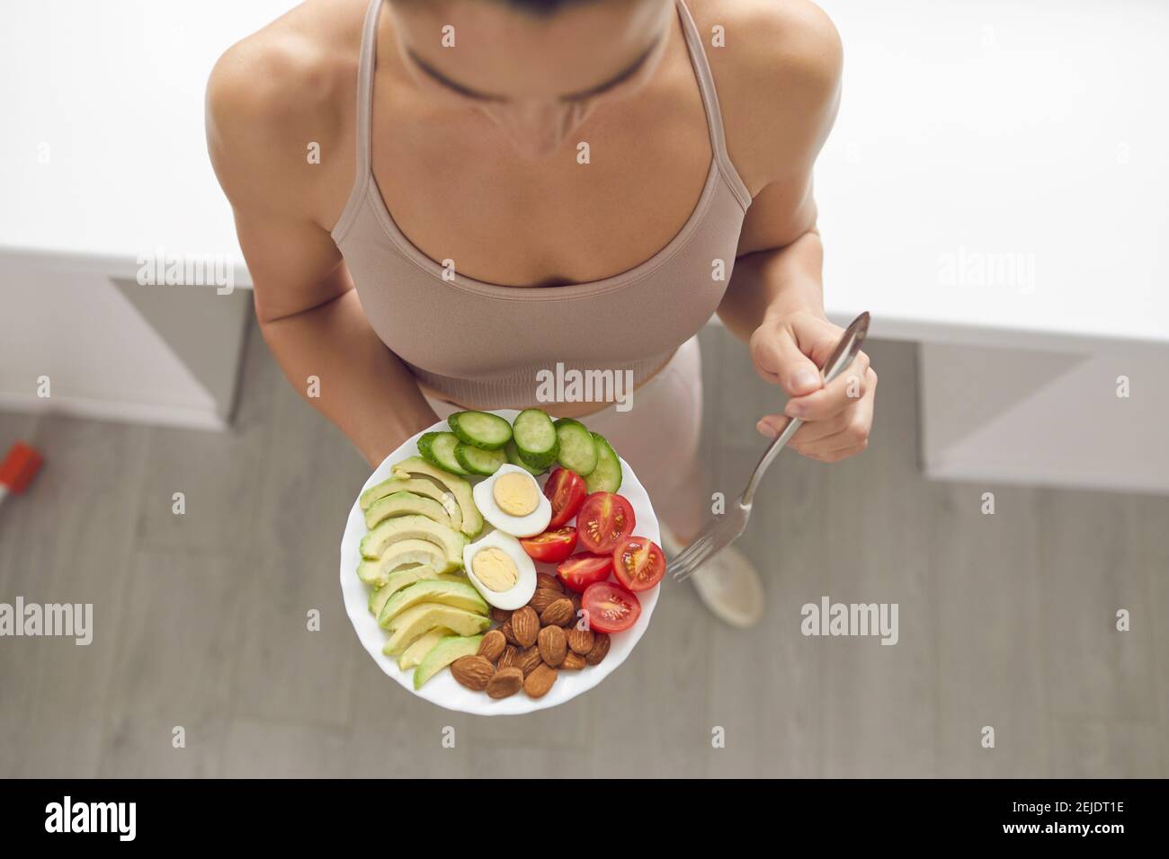 Woman having healthy meal of almonds, egg, sliced avocados, tomatoes and cucumbers Stock Photo