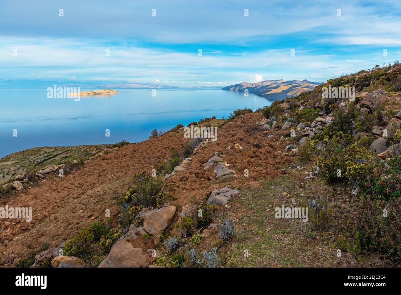 Agriculture field terraces on Isla del Sol (Sun Island) with the sunlit Moon Island, Titicaca Lake, Bolivia. Stock Photo