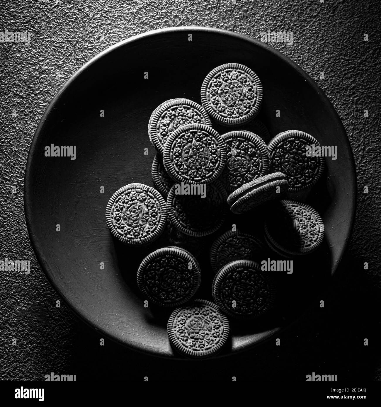 textured cookies in a black plate on a dark background, art food concept, square photo. Stock Photo