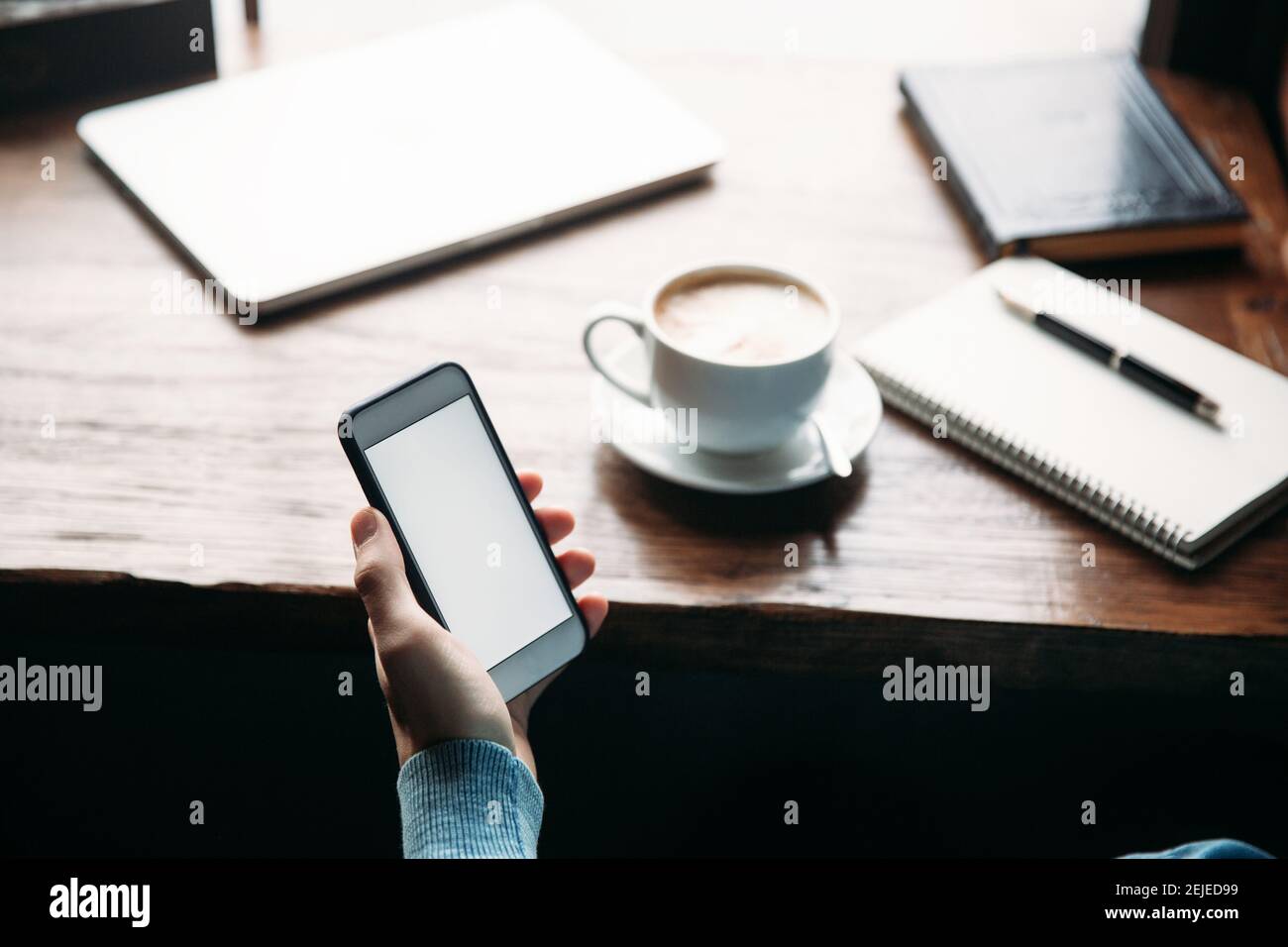 Man using phone inside a restaurant while drinking coffee Stock Photo
