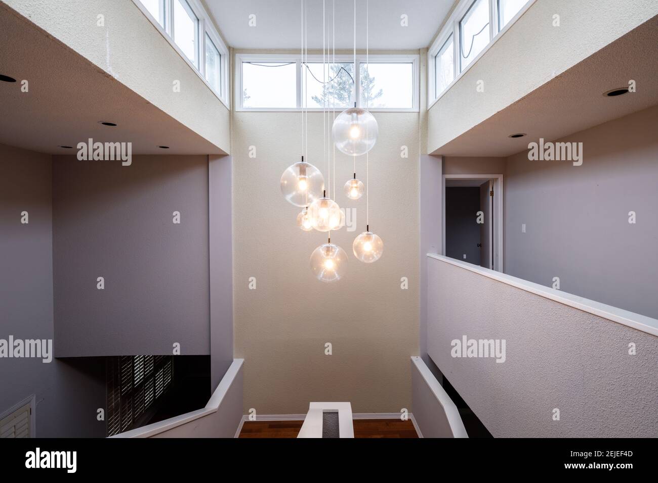 A contemporary chandelier hanging over a stairwell in a large home